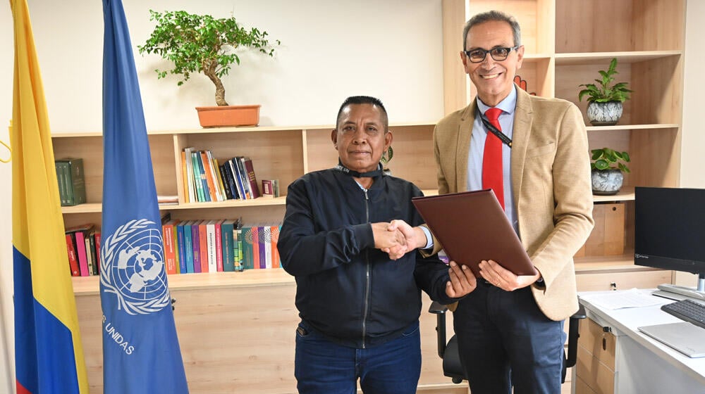 Representantes de ACATISEMA y UNFPA sostienen documento y estrechan la mano